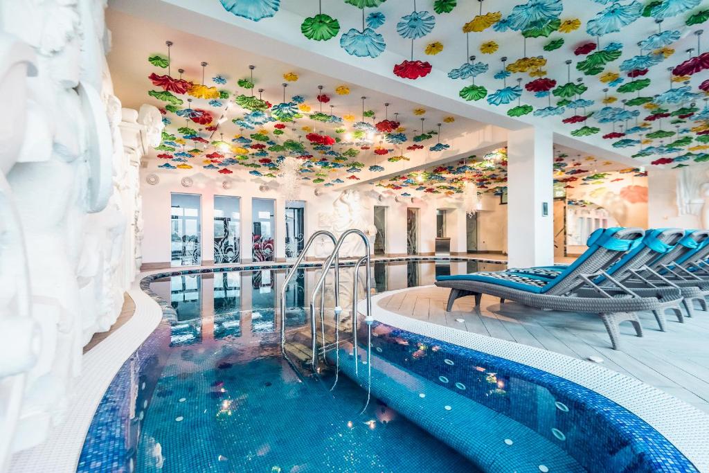 une piscine dans un hôtel avec un plafond rempli de fleurs dans l'établissement Villa Galleria, à Colibiţa