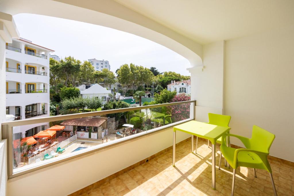 a balcony with a green table and chairs and a large window at Clube do Lago Hotel in Estoril