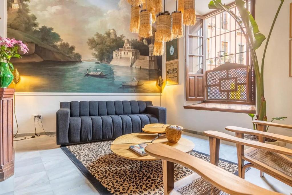 una sala de estar con un sofá azul y una pintura en Designer Apartment en Sevilla