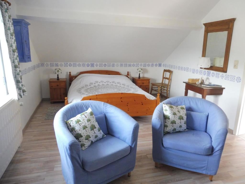 a bedroom with two blue chairs and a bed at La Lustinoise in Lustin