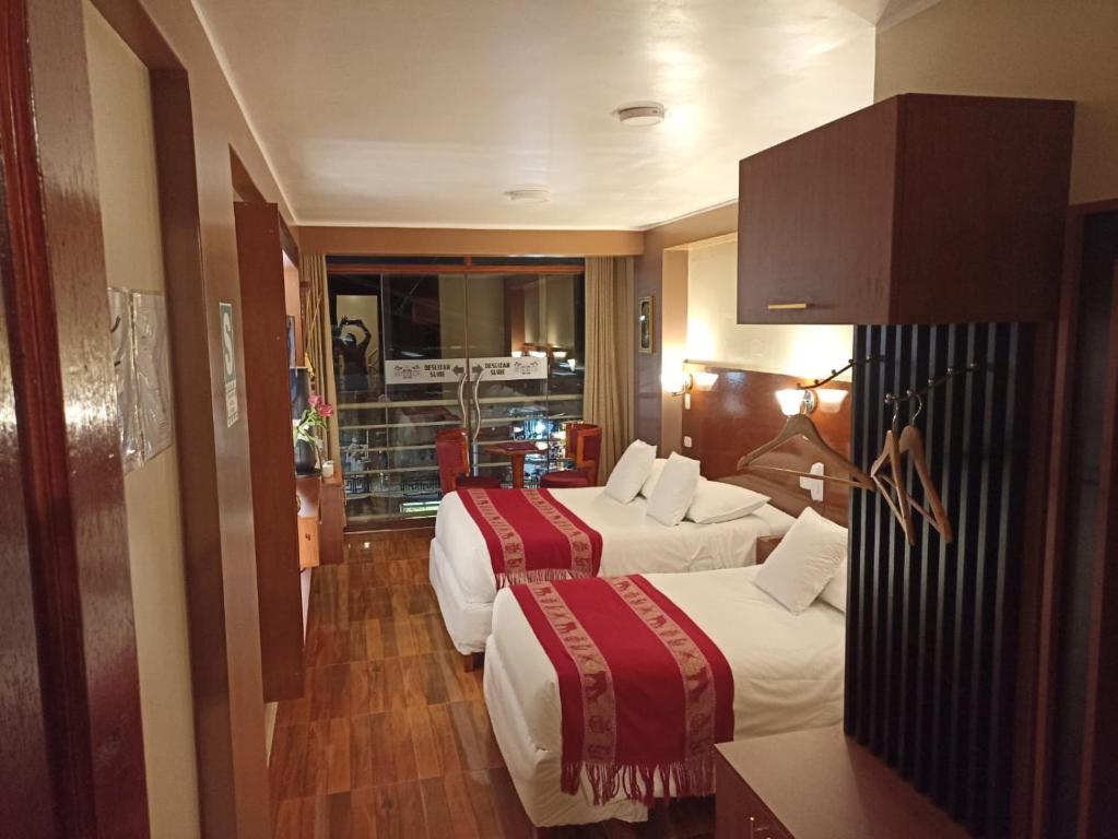 マチュピチュにあるHs Tierra Inのベッド2台とキッチンが備わるホテルルームです。