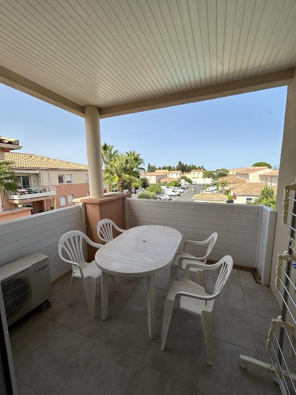 einen weißen Tisch und Stühle auf dem Balkon in der Unterkunft Appartement moderne en résidence avec piscine in Mèze