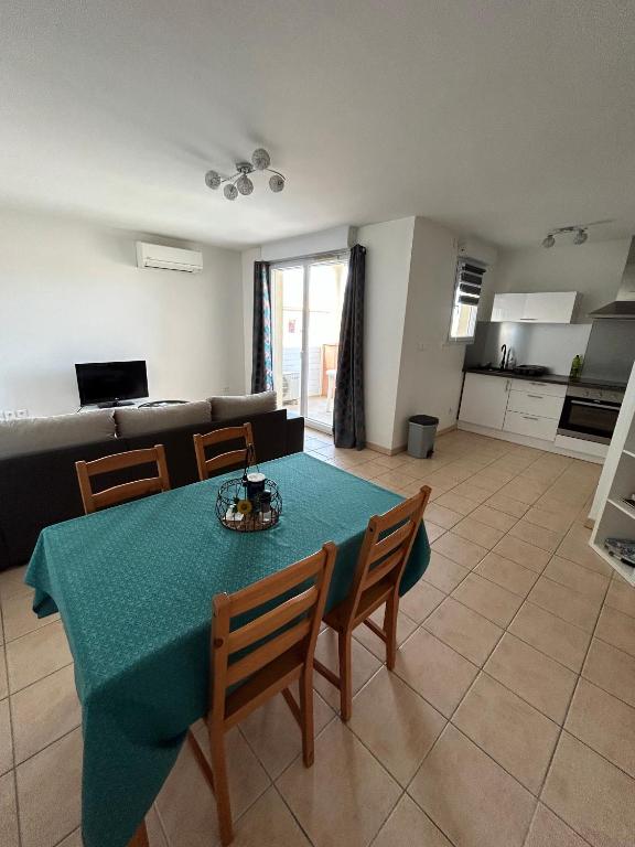 ein Wohnzimmer mit einem Tisch, Stühlen und einem Sofa in der Unterkunft Appartement moderne en résidence avec piscine in Mèze