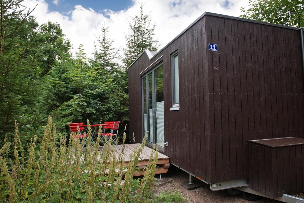 a dark brown tiny house in the woods at Tiny House Nature 11 - Green Tiny Village Harz in Osterode