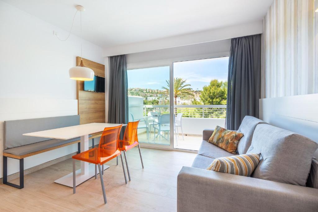 een woonkamer met een bank en een tafel met uitzicht bij Casablanca Apartments, Santa Ponsa in Santa Ponsa