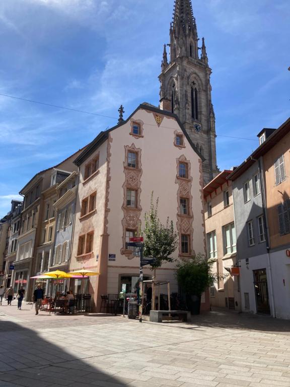 un bâtiment avec une tour d'horloge et une église dans l'établissement Gîte des Victoires, à Mulhouse