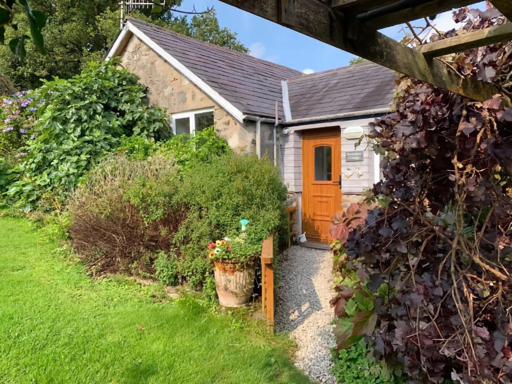 a cottage with a orange door in a garden at Cozy Cottage - Near Brew Pub / Snowdonia National Park. in Caernarfon