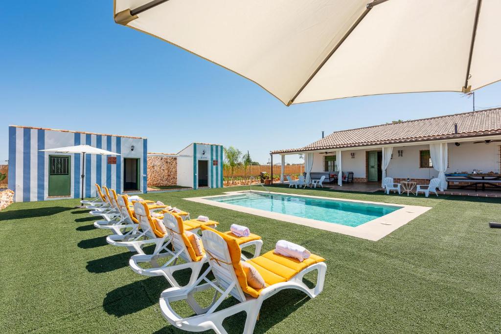 uma fila de espreguiçadeiras sentadas ao lado de uma piscina em Casa Rural Reifs 