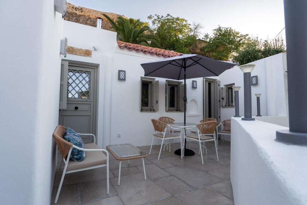 a patio with a table and chairs and an umbrella at Villa Hermes in Anafiotika Athens ! in Athens