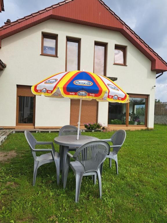 einen Tisch mit einem Regenschirm vor einem Haus in der Unterkunft Ogrodowe Noclegi 2 