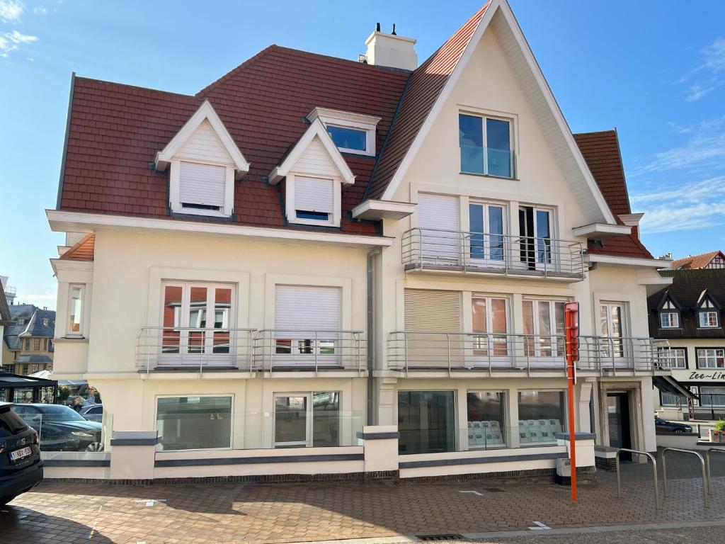 a large white house with a red roof at De Haan App 1 in De Haan