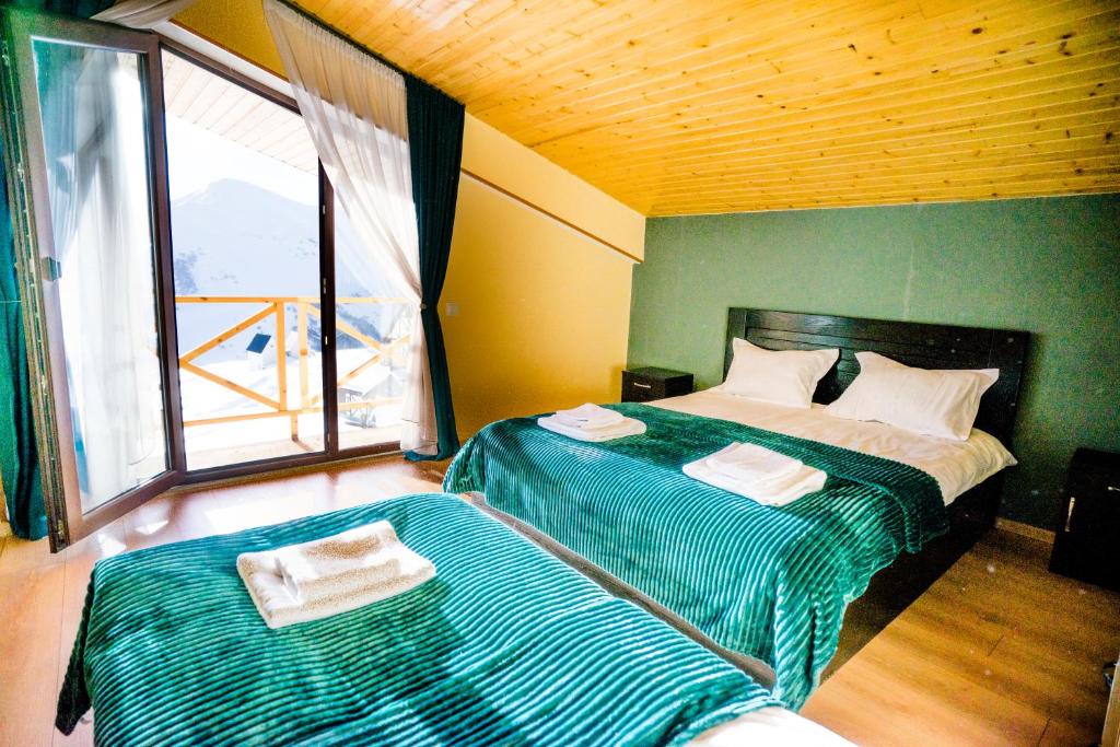 a bedroom with two beds with green and white sheets at Sunny hill in Gudauri