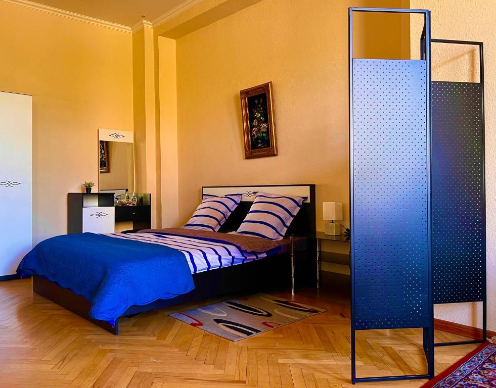 1 dormitorio con 1 cama con sábanas azules y espejo en Old Ubani Apartment, en Tiflis