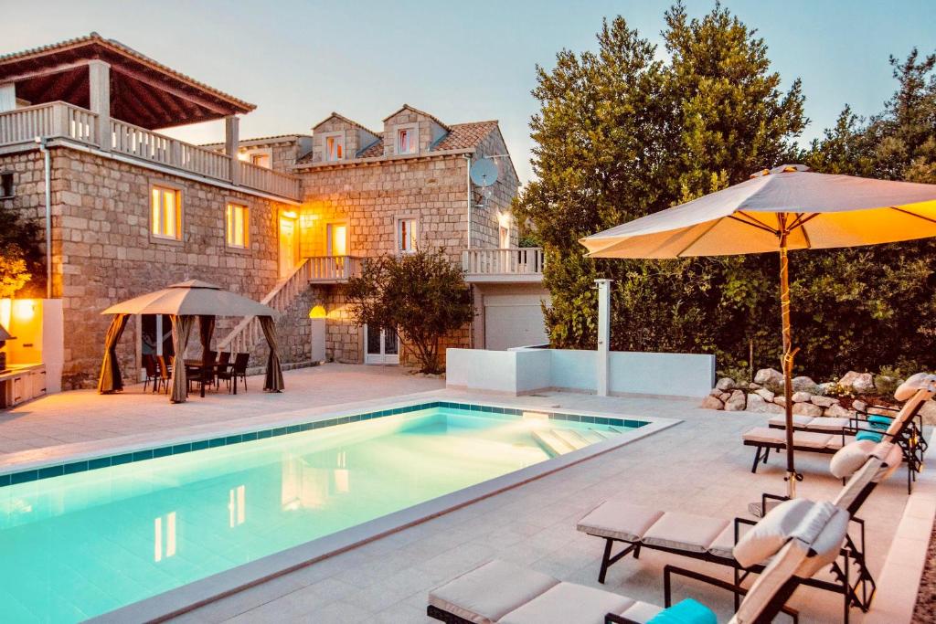 a pool with chairs and umbrellas next to a house at Villa Pendo 1450- Full private luxury property in Komaji