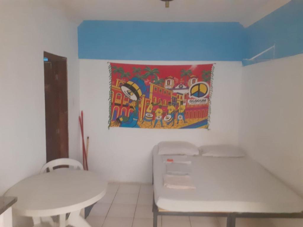 a room with two white tables and a painting on the wall at apartamento itapua in Salvador