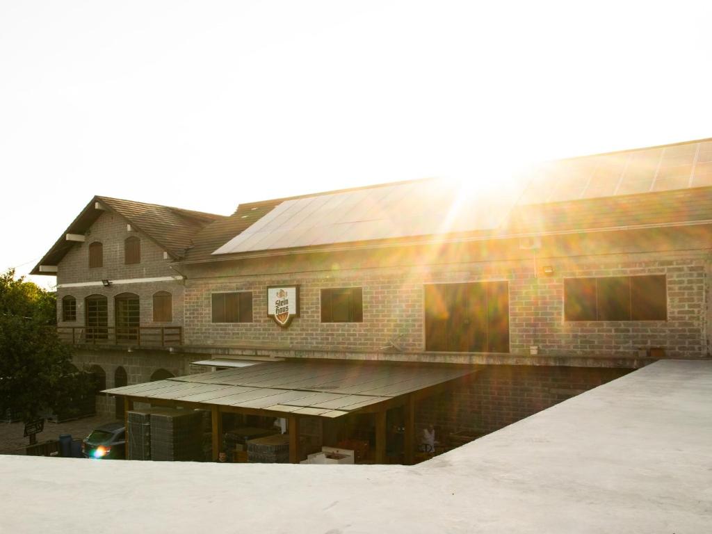 un edificio de ladrillo con el sol brillando en él en Pousada e Cervejaria Stein Haus en Picada Cafe