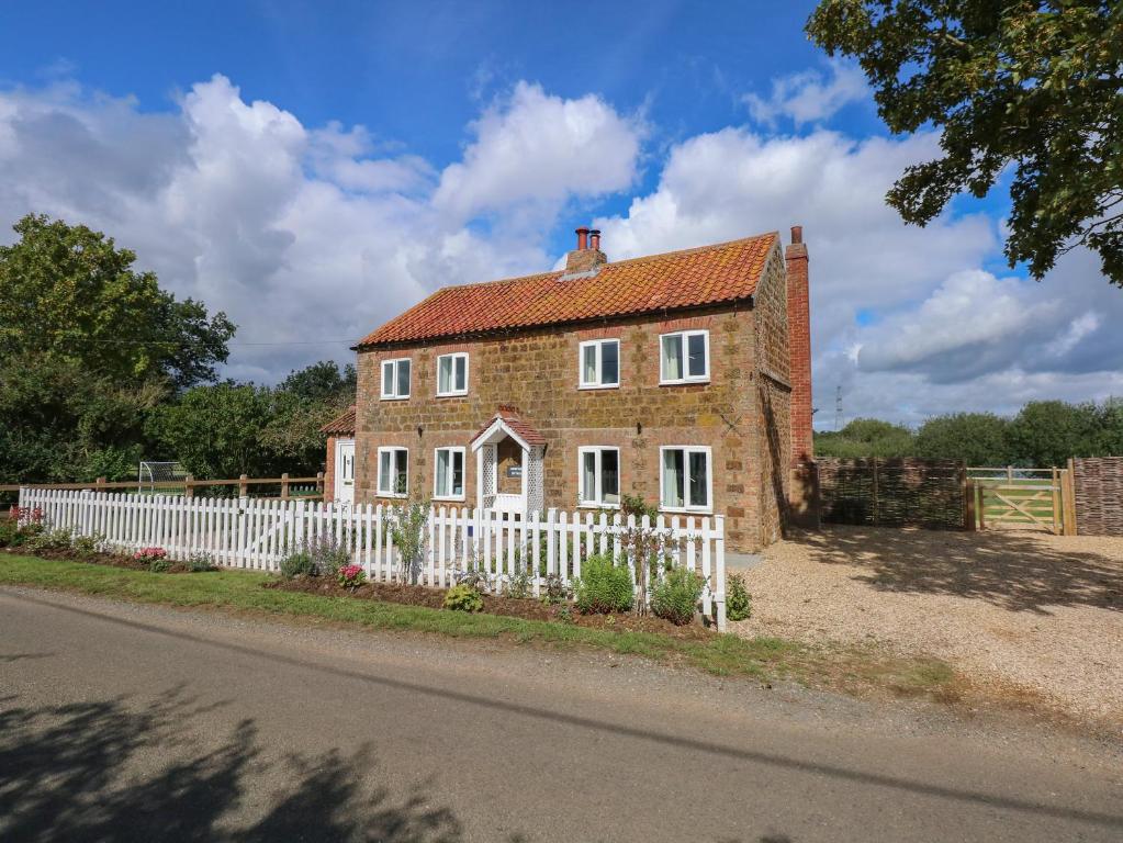 an old brick house with a white fence at Horseshoe Cottage in Pentney