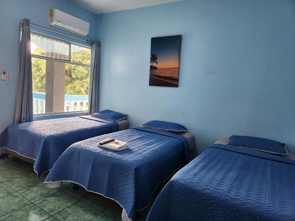 Cette chambre comprend 3 lits et une fenêtre. dans l'établissement Hotel y Restaurante El Marino, à Santa Cruz