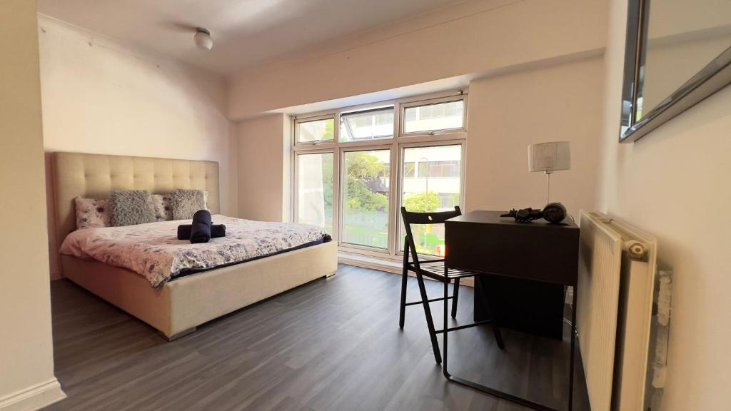 a bedroom with a bed and a desk and a window at Aldgate Rooms in London