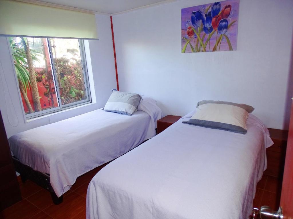 two beds in a room with a window at El Rincon de los Poetas in Nueva Imperial