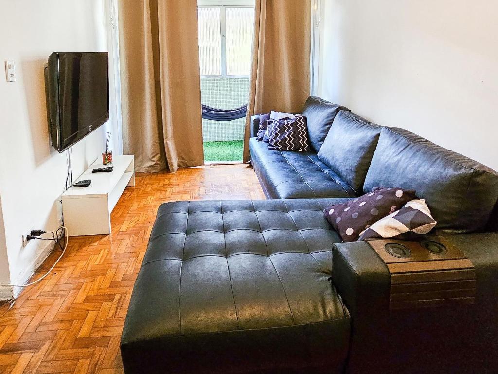 uma sala de estar com um sofá de couro preto e uma televisão em Apartamento Alameda Santos - By Capsula Hotel em São Paulo