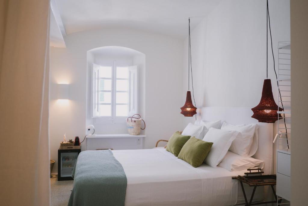a bedroom with a white bed with green and white pillows at Can Set in Cadaqués