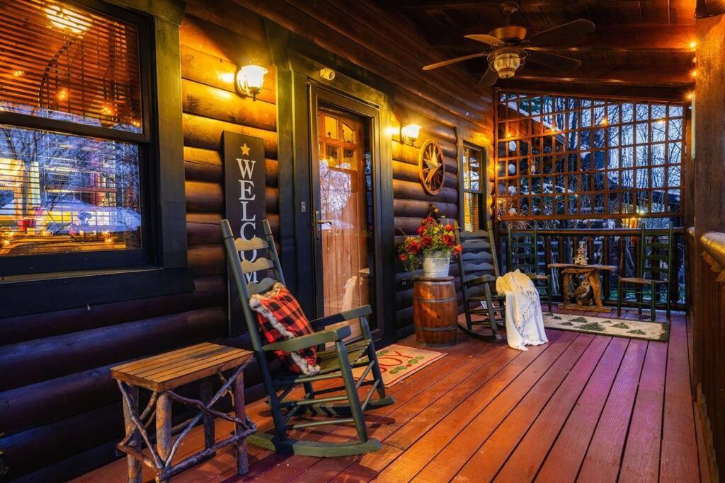 a porch of a log cabin with two chairs and a table at Lazy Fox Hideout in Sevierville