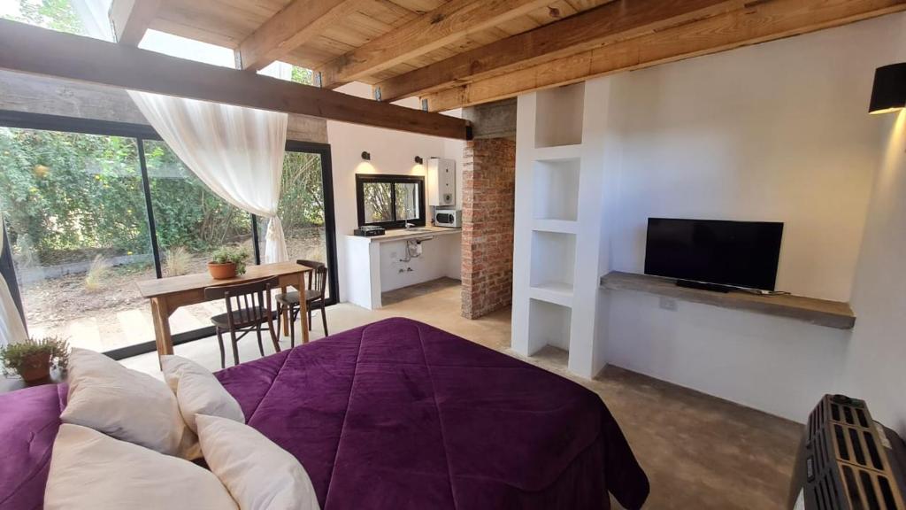 1 dormitorio con cama, mesa y TV en Cabaña del Cedro Azul, San Lorenzo en Salta