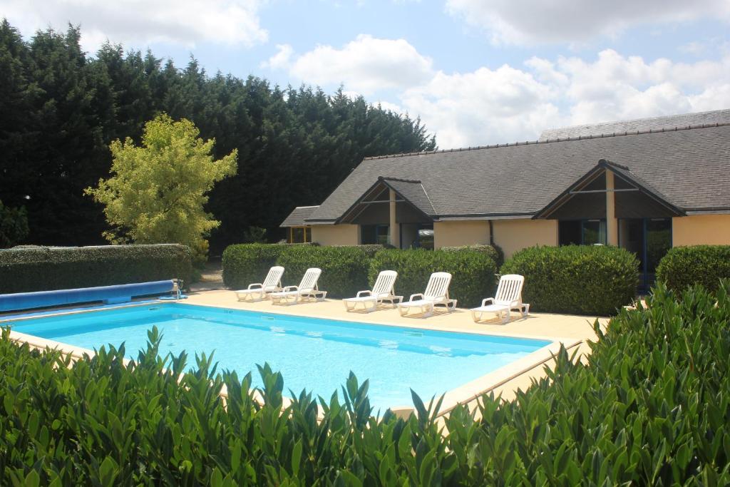 a swimming pool with lounge chairs and a house at Les Dineux Village in Trémeur