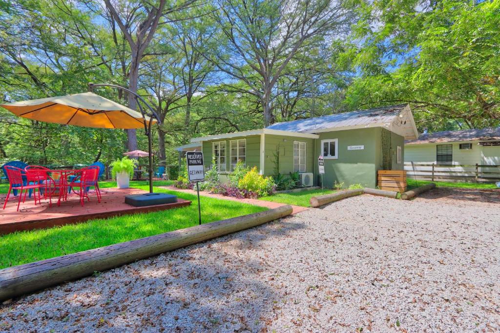 a tiny house with a table and an umbrella at Creekside Cabins - The Getaway in Wimberley