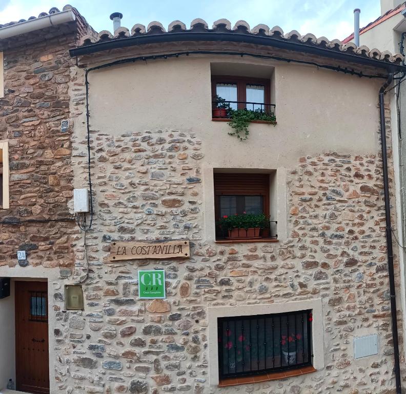 um edifício de pedra com duas janelas e um sinal nele em Casa Rural LA COSTANILLA em Lituénigo