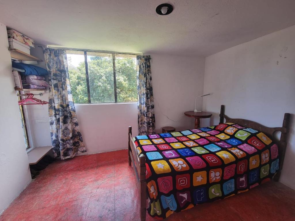 a bedroom with a bed with a colorful quilt at Cálida habitación en casa hogareña. Ambiente familiar. in Teziutlán