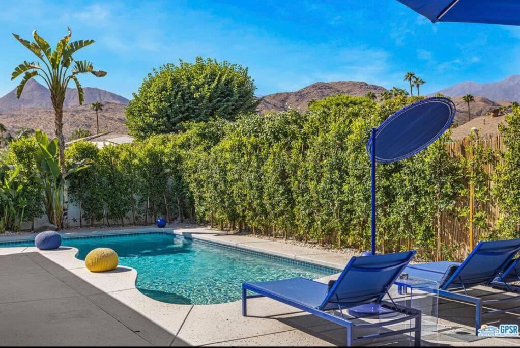 - une piscine avec 2 chaises et un parasol dans l'établissement wonderfully reimagined 3bd 2bath mid-century palm springs home, à Palm Springs