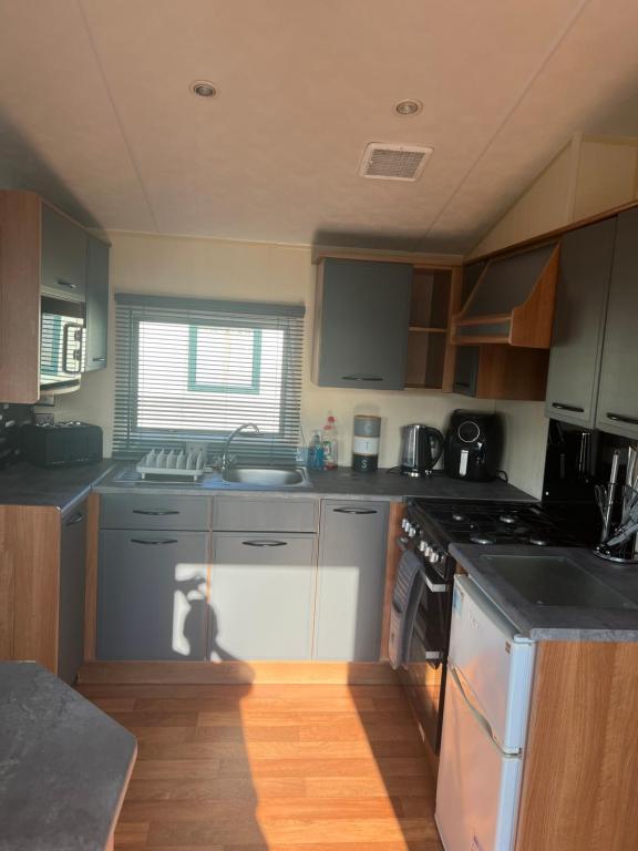 a kitchen with a sink and a stove at Lisa and Laddy Caravan Hire in Meliden