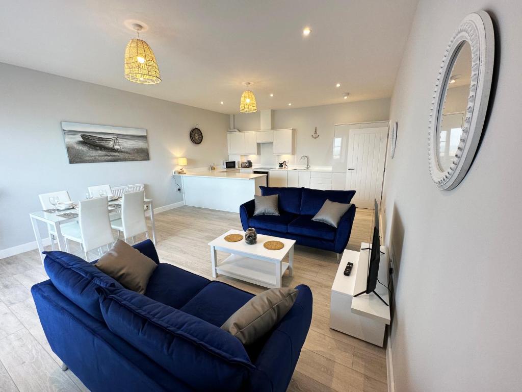 a living room with a blue couch and a kitchen at Ocean View Suite - Near Hythe - On Beach Seafront - Private Parking in Dymchurch