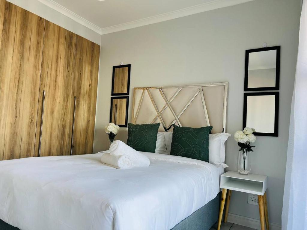1 dormitorio con 1 cama blanca grande con almohadas verdes en The Blyde en Pretoria