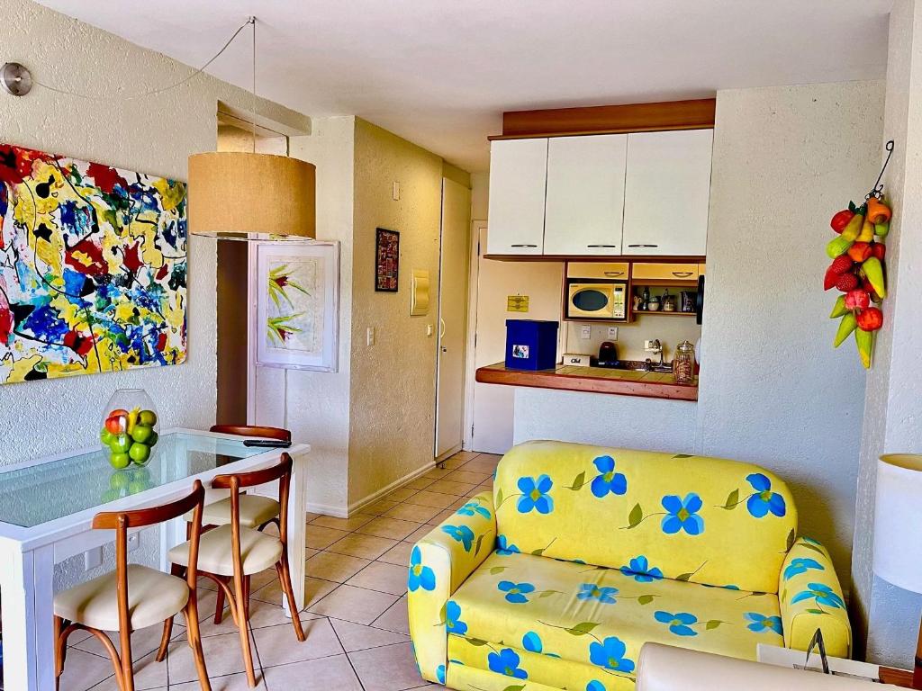 a kitchen and a living room with a couch and a table at Apartamento Dentro Resort Costao do Santinho NOT ALL INCLUSIVE in Florianópolis