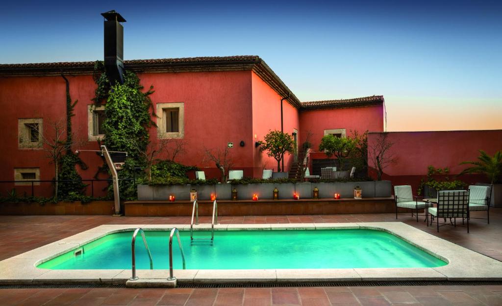 a swimming pool in front of a red building at Izan Trujillo in Trujillo
