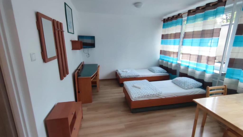 Habitación pequeña con 2 camas y mesa. en Pokoje 24h ul. Bagrowa Kraków en Cracovia