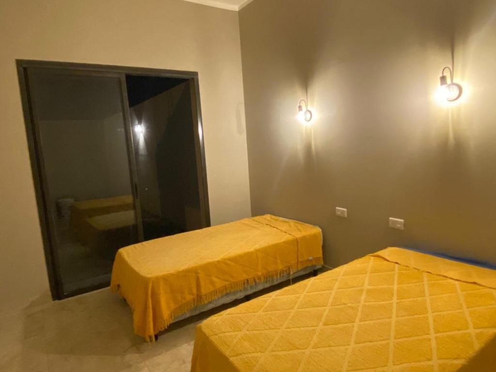two beds in a room with yellow sheets and a mirror at Casa del Sol in Salta