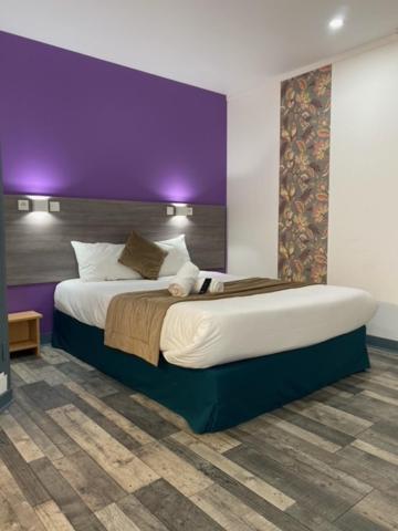 ディジョンにあるFASTHOTEL A Dijonの紫の壁のベッドルーム1室(大型ベッド1台付)