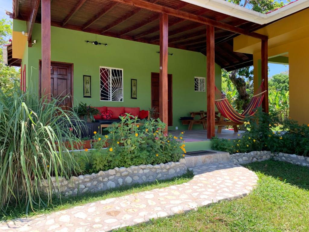 Green Queendom Farm and Lodging في Oracabessa: منزل أخضر مع أريكة حمراء في ساحة