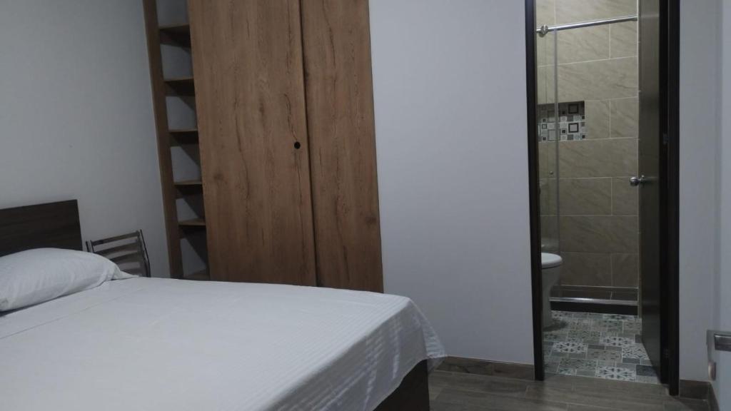 a bedroom with a bed and a bathroom with a shower at Hotel Guadalupe Acacías in Acacías