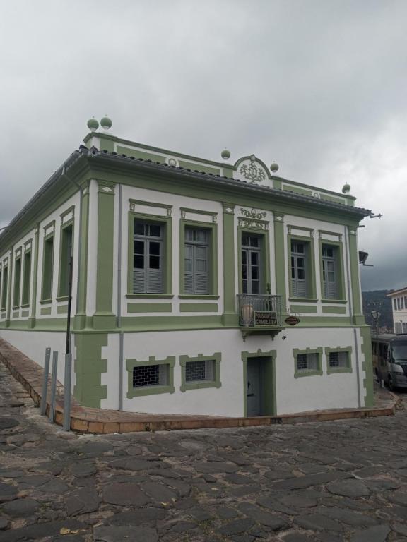 ein grün-weißes Gebäude mit einer Uhr oben in der Unterkunft Pousada Gameleira in Diamantina