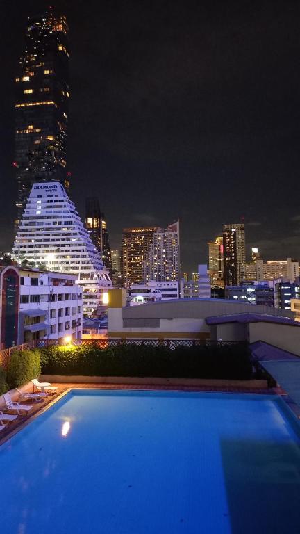 een uitzicht op de skyline van de stad 's nachts met een zwembad bij Panoramic City View Room at Silom in Bangkok