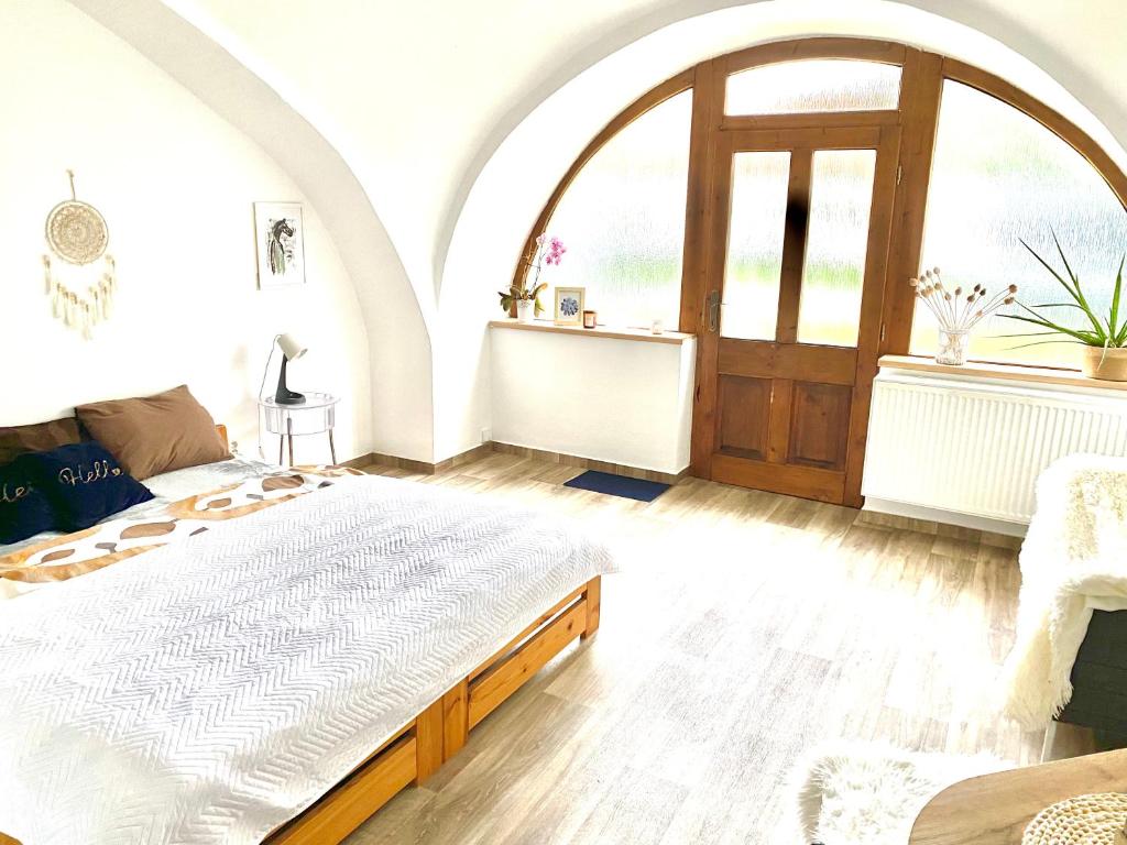ein Schlafzimmer mit einem großen Bett und einem großen Fenster in der Unterkunft Apartmán v koňském areálu Židovice in Louny