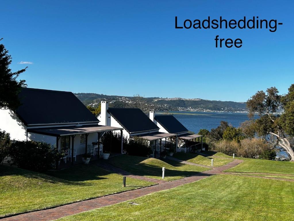 a row of houses with a lake in the background at Blu Belle Lagoon Cottage in Knysna