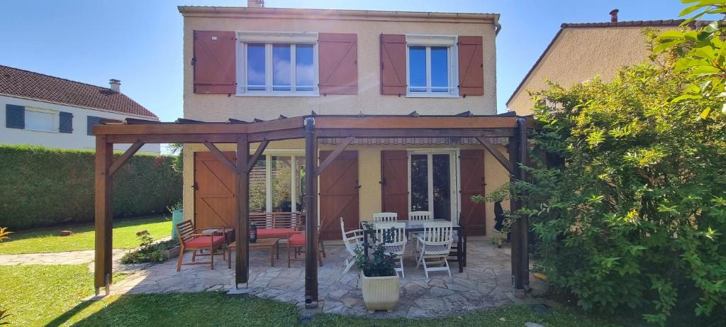 a gazebo with a table and chairs in front of a house at Un Havre de Paix in Villepinte