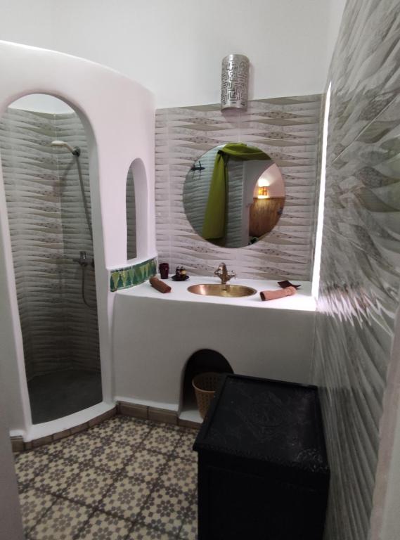 y baño con lavabo y ducha con espejo. en Riad Bab Lakhmiss, en Marrakech