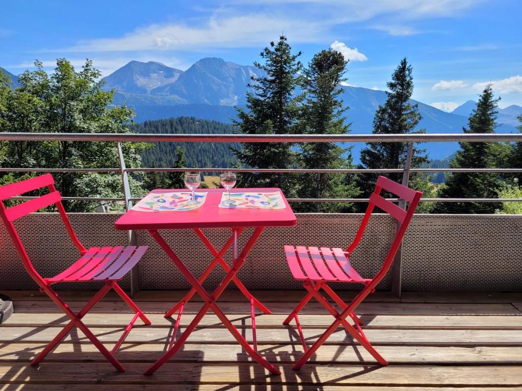 a pink table and two chairs on a deck with mountains at Arolles D21 - Chamrousse 1700 - Les Villages du Bachat in Chamrousse
